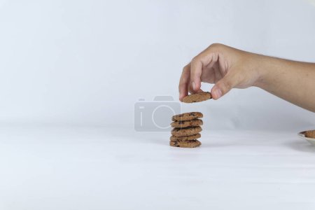 Photo for Hands stacking cookies on a white background. Human hand taking oat cookie from a stack - Royalty Free Image