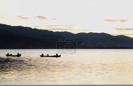 Photo for Fishermen on the lake from a boat at sunset. Limboto Lake, Gorontalo, Indonesia. beautiful sky in the afternoon - Royalty Free Image