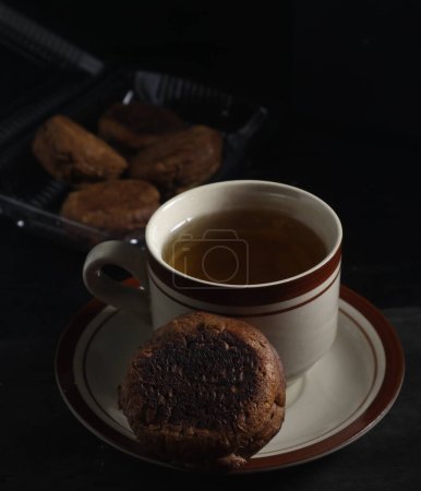 Apang bale cake or Apang bakar, and a cup of tea isolated on black background. Indonesian cake
