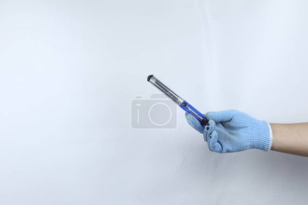 Téléchargez les photos : Pompe à dessouder en métal à main gantée isolée sur fond blanc - en image libre de droit
