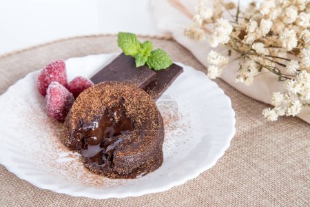 "Petit gateau" delicious chocolate dessert, fluffy cake with melted chocolate cream inside. Served and ready-to-eat homemade cake on a white plate.