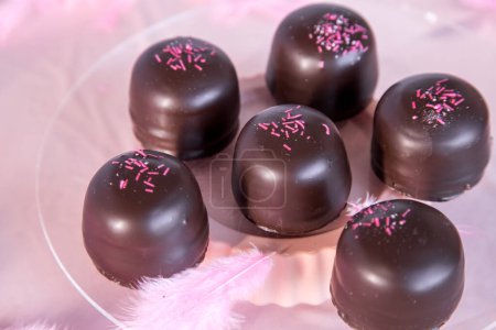Biskuit-Marshmallow-Bonbons mit Schokolade und Vanille-Waffel bedeckt, darunter, auf rosa Hintergrund.
