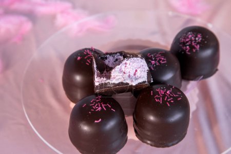 Sponge marshmallow candy covered in chocolate and vanilla wafer underneath, on a pink background.