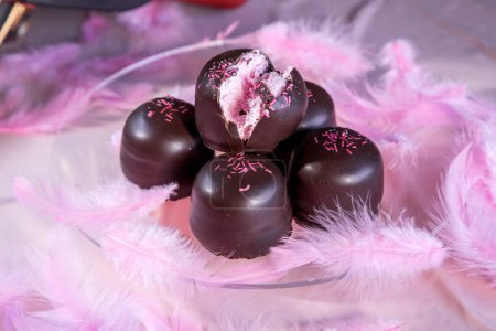 Bonbons à la guimauve éponge recouverts de chocolat et de galette de vanille en dessous, sur un fond rose.