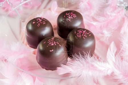 Biskuit-Marshmallow-Bonbons mit Schokolade und Vanille-Waffel bedeckt, darunter, auf rosa Hintergrund.