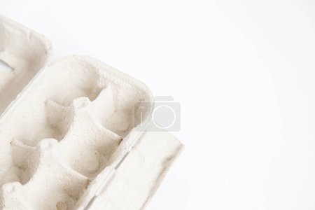Photo for Detail of empty and open recycled cardboard egg carton in the corner of the image on a white background. Close up and copy space. - Royalty Free Image