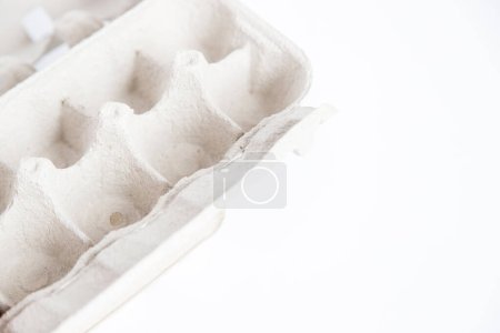 Photo for Detail of empty and open recycled cardboard egg carton in the corner of the image on a white background. Close up and copy space. - Royalty Free Image