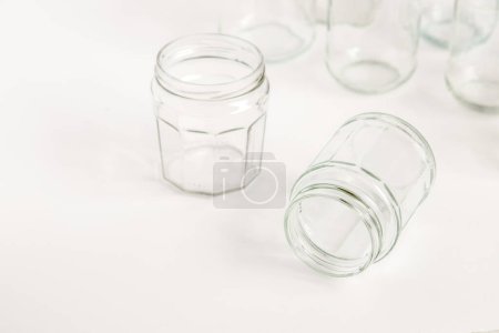 Téléchargez les photos : Assortiment de récipients en verre sans couvercles sur fond blanc, recyclage. Concept de seconde vie aux matériaux, différentes utilisations pour les flacons en verre. - en image libre de droit