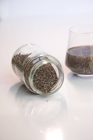 Pile of edible chia seeds from the Salvia hispanica plant. Very healthy functional food to use in various recipes. Cup containing the hydrated seeds.