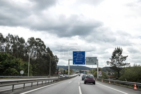 Section de l'autoroute A3, Douro Minho, qui relie Porto à Valenca, Portugal. Affluence des véhicules dans les deux sens. Panneau d'information, directions. Belle journée avec de hauts nuages.