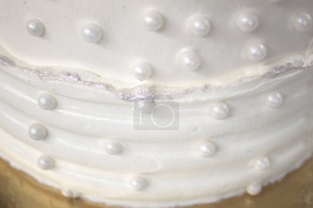 Gâteau de fête blanc avec glaçage blanc et perles, conception de gâteau. Gâteau fait à la main pour une occasion spéciale de célébration. Détails particuliers.