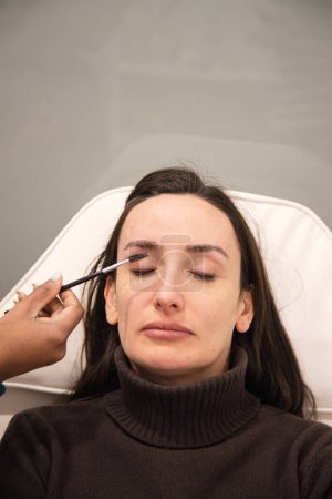 Femme caucasienne enlever les cheveux des sourcils avec la technique du fil fait par le styliste des sourcils. Du fil. Étapes du processus. Gros plan