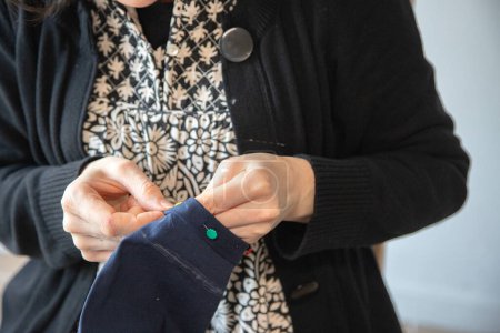 Téléchargez les photos : Détail des mains d'une femme caucasienne faisant du travail de couture dans sa maison. Processus et exécution. Mesurer, couper et coudre pour refaire une paire de pantalons. - en image libre de droit