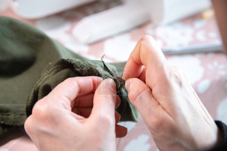 Détail des mains d'une femme caucasienne faisant du travail de couture dans sa maison. Processus et exécution. Mesurer, couper et coudre pour refaire une paire de pantalons.