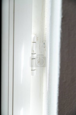 Weißes Innenscharnier aus PVC oder Kunststoff. Detail einer Tür oder eines Fensters. Konzeptzustand der Erhaltung und Sauberkeit von Materialien, Feuchtigkeit sowie Schimmel und Schmutz.