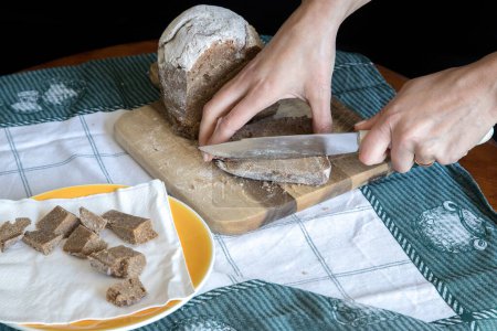Broa de Avintes, traditionelles Brot aus Vila de Avintes, Vila Nova de Gaia, Portugal. Dunkles Brot mit Maismehl, Roggen und Gerste. Person schneidet Brot