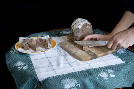 Broa de Avintes, traditionelles Brot aus Vila de Avintes, Vila Nova de Gaia, Portugal. Dunkles Brot mit Maismehl, Roggen und Gerste. Person schneidet Brot