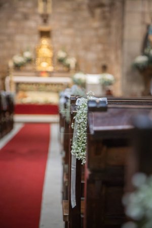 Floral ornamentation inside a worship space, church. Festive decoration for wedding event. Flower arrangements predominantly white and green.