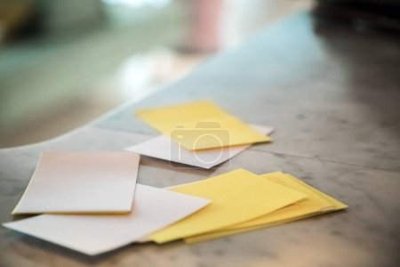 Blank white and yellow sheets of paper spread out on top of a flat surface, table. Selective focus.