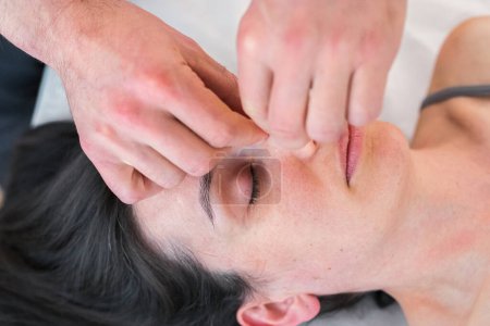 Therapist doing nose alignment treatment to help patient breathe better. Techniques of treatment by manipulation with the hands.