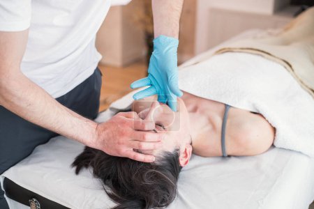 Osteopathischer Therapeut, der kaukasische Frauen mit Kieferproblemen, Unterkieferausrichtung behandelt. Behandlung zur Schmerzlinderung und Verbesserung des Gesundheitszustandes des Patienten.