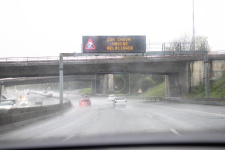 Image of the section of the internal beltway, VCI, Porto, Portugal. Local traffic during a day of bad weather conditions with heavy rain. Information panel "In rain, moderate speed".