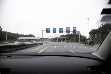 Section of the A3 motorway, Portuguese connection Minho, Valena, Porto, Portugal. Tolls and fees section. Text "Manual route". Interior view of the vehicle on a rainy and cloudy day.