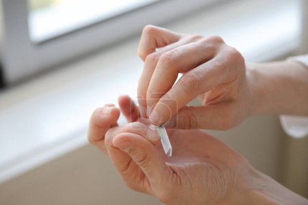 A person carefully filing their nails at home, focusing on self-care and grooming. Close up