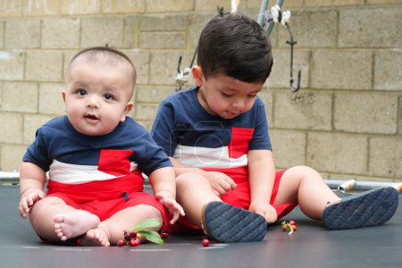 Photo for 2 Year's Old and 4 Months Old Baby Brothers are  Enjoying on Trampoline in the Home Garden on a Beautiful Day over Luton, England UK. Gorgeous Close Up Image Was Captured on  July 23rd, 2023 - Royalty Free Image