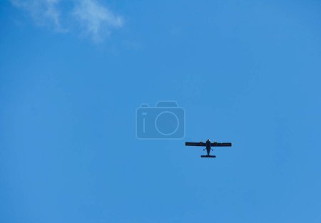 Photo for A small black plane flying against the sky. - Royalty Free Image