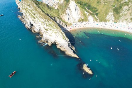 Foto de Hermosa vista de ángulo alto de la gente está disfrutando del clima británico caliente en barcos y nadar en la playa del océano de Durdle Vista de la puerta del mar Aguas de Inglaterra Gran Bretaña. Imagen capturada el 9 de septiembre de 2023 - Imagen libre de derechos