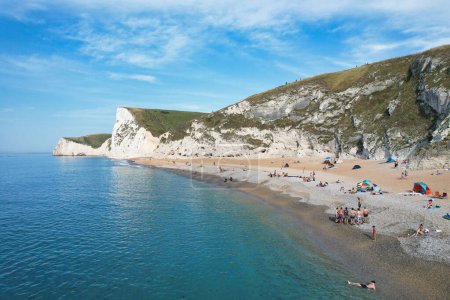 Photo for Aerial View of People are Enjoying Hot Summer Day of England at Durdle door Natural Beach During Their Holidays. Beautiful Tourist Attraction Captured with Drone's Camera on Sep 9th, 2023, England UK - Royalty Free Image