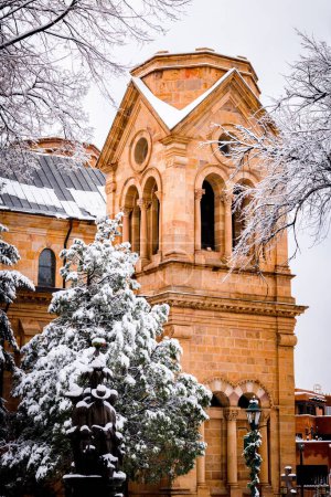 Téléchargez les photos : Scène hivernale enneigée avec vue verticale sur le clocher de l'église et les arbres enneigés à Santa Fe, Nouveau-Mexique - en image libre de droit