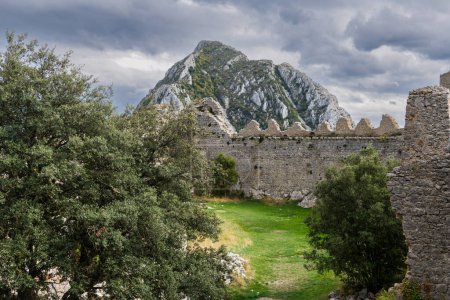 Téléchargez les photos : Château ruines remparts du Château de Puilaurens sous un sommet de montagne sous un ciel orageux dans les Pyrénées françaises - en image libre de droit