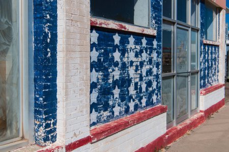 Téléchargez les photos : Devant un bâtiment abandonné et altéré peint dans les étoiles et les rayures du drapeau américain - en image libre de droit