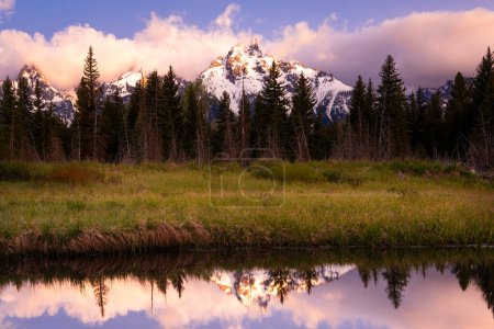 Téléchargez les photos : Lever de soleil sur les sommets enneigés des montagnes et de beaux nuages roses et violets reflétés dans un étang calme dans le parc national de Grand Teton, Wyoming - en image libre de droit