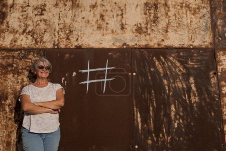 eine reife Frau neben einer Stadtmauer mit einem Hashtag auf dem Hintergrund