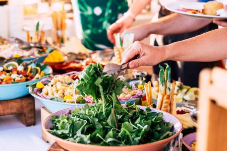 close up of view of table full of food with someone taking vegetables of the table to celebrate  