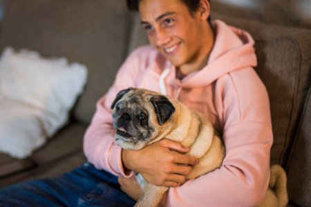 Mops und Teenager gemeinsam auf dem Sofa - Haustier und Haushund zu Hause 
