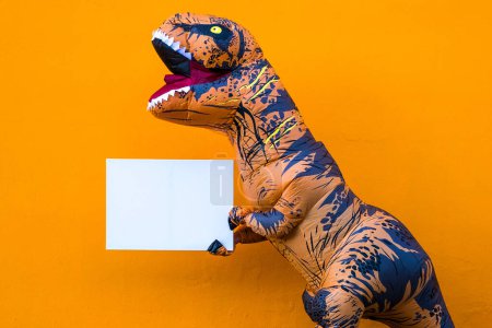 Téléchargez les photos : Gros plan et portrait d'un t-rex tenant un livre blanc pour écrire votre texte ici - dinosaure tenant un espace de copie - en image libre de droit