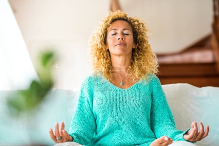 Téléchargez les photos : Femme faire du yoga à la maison et se détendre sur le canapé seul à l'intérieur - mode de vie sain - en image libre de droit