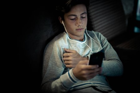 adolescent portant un casque seul à la maison sur le canapé avec son ordinateur portable travaillant ou jouant ou regardant des vidéos