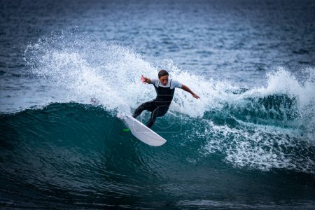 Téléchargez les photos : Un homme chevauchant une grande vague bleue extrême dans l'océan - heure d "été et profitant de vacances - en image libre de droit