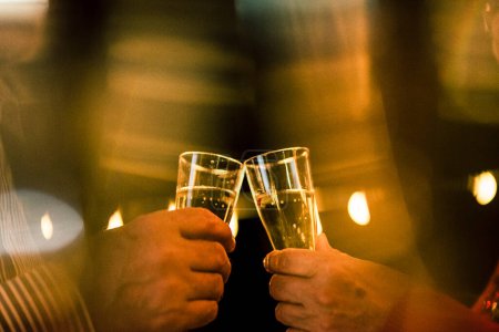 Téléchargez les photos : Gros plan de deux mains avec verre avec champagne cliquetis ensemble pour célébrer la nouvelle année ou quelque chose de fête seul - en image libre de droit