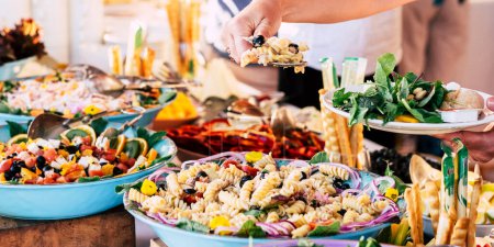 Photo for Close up view of people friends hands taking food from catering table during party celebration - food on a table -colored background and together - Royalty Free Image