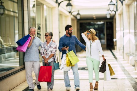 Photo for Group of four people attended the mall going shopping together with shopping bags on their hands - seniors and adults at the stores - Royalty Free Image