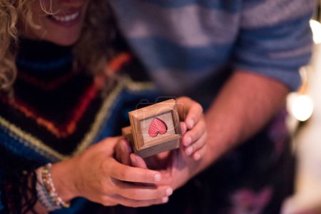 Foto de Primer plano de las manos de dos adultos en una relación juntos buscando un regalo como una caja con un anillo de aniversario - pareja de hombre y mujer - Imagen libre de derechos