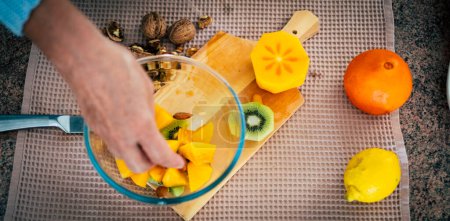 Top view of woman hands cutting fresh oranges with knife. Female making fresh fruit salad. Vegetarian concept