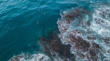 Téléchargez les photos : Belles et grandes vagues bleues et vertes qui se brisent - océan Pacifique ou Atlantique - mer bleue et endroit idéal pour surfer - au-dessus et vue sur le dessus d'un drone - trois surfeurs attendent aux vagues - en image libre de droit