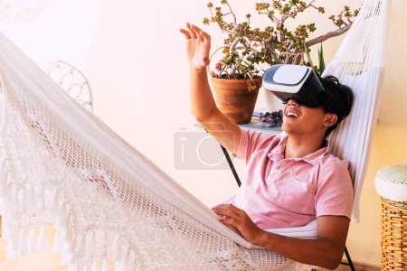 Photo for Happy teenager having fun with his new VR glasses in the terrace of his house on an hammock - adult trying to touch something he see in the glasses of the future - Royalty Free Image
